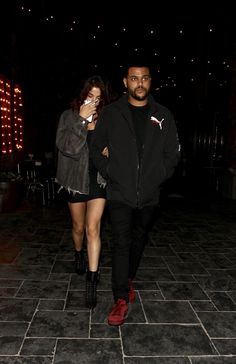 a man and woman walking down a street at night