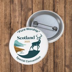 a white button with the words scotland on it and a deer standing in front of a lake