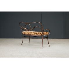 an iron bench with leopard print upholstered seat and back rests against a gray wall