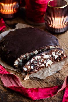 a piece of chocolate and nuts bar sitting on top of a wooden table next to two candles