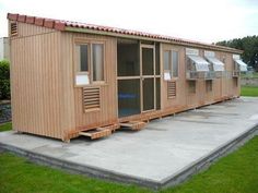 a group of wooden cabins sitting on top of a lush green field next to a parking lot