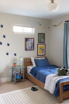 a bed room with a neatly made bed and blue comforter on the floor next to a window