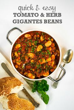 a bowl filled with stew next to bread and parsley on a white tablecloth