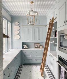 a ladder is hanging from the ceiling in a kitchen with blue cabinets and white walls