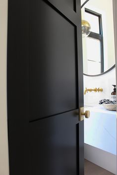 an open door leading to a bathroom with a sink and mirror on the wall behind it