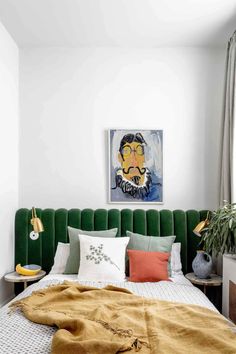 a green headboard in the corner of a bedroom with pillows and blankets on it