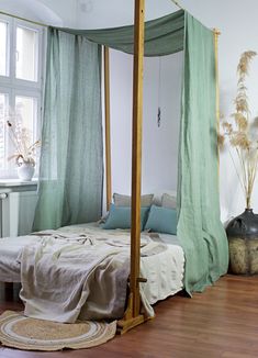 a canopy bed sitting in the middle of a bedroom next to a window with green drapes