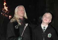 two men dressed in harry potter costumes standing next to each other with their eyes closed