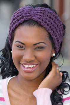 a woman wearing a knitted headband smiling at the camera with her hand on her shoulder