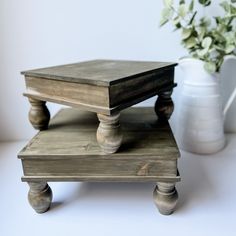 two wooden trays sitting on top of each other next to a vase with flowers