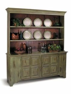 an old wooden china cabinet with plates on it