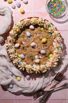 a cake with sprinkles and candy on it sitting on a table next to utensils