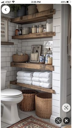 a white toilet sitting in a bathroom next to a wooden shelf filled with lots of towels