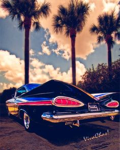 a classic car parked in front of palm trees