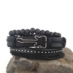 This guitar bracelet set complements your love for music. The all black bracelets are versatile and can be worn with any of your outfits. You can wear the bracelets together as a set or each one separately to create a different everyday. Every set is handmade with care. Product Information *Set comes with 3 bracelets *Material: leather/PU leather *Metals Type: alloy *Clasp Type: sliding knots *Adjustable Length: around 7 - 8.5 inches Adjustable Black Punk Wristband, Black Band Wristband For Concerts, Black Rock Style Wristband As Gift, Edgy Band Bracelet For Concerts, Edgy Band Bracelet For Concert, Black Punk Bracelets For Festival, Black Punk Festival Bracelets, Edgy Black Band Bracelets, Adjustable Black Punk Beaded Bracelets