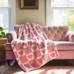 a pink couch sitting next to a window covered in a blanket