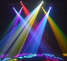 three spotlights are shining brightly on a stage with colored lights in the dark,