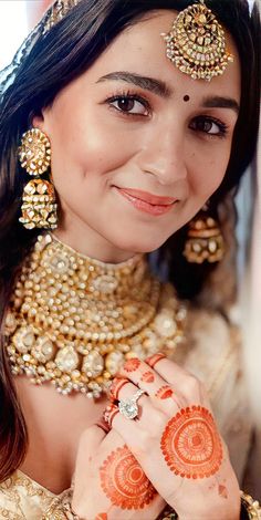 a woman with henna on her face and hands, smiling at the camera as she poses