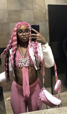 a woman with pink hair and glasses is taking a selfie in front of a mirror