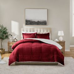 a bed with red comforter and pillows in a bedroom