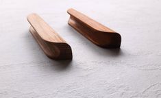 two wooden spoons sitting on top of a white table next to eachother