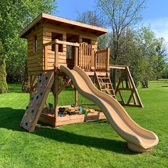 a wooden playset with a slide and climbing frame in the grass near some trees