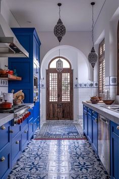 a kitchen with blue cabinets and tile flooring next to an arched doorway that leads into the dining room