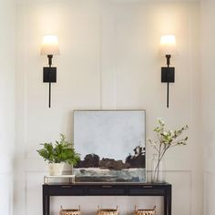 a living room with two lamps on the wall and a bench in front of it