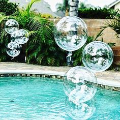 some clear balls floating in the air near a pool