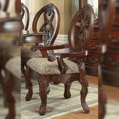 an ornate wooden chair with upholstered seat and arm rests in front of a mirror