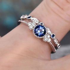 a woman's hand wearing a blue and white ring with diamonds on it,