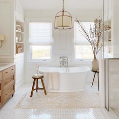 a bathroom with a large white bathtub and wooden stools in front of the tub