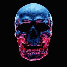 a skull with red and blue paint on it's face, in the dark