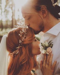 a bride and groom kissing in the woods