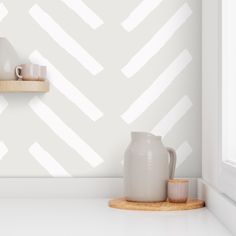 a white vase sitting on top of a wooden shelf