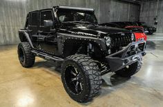 a black jeep parked in a garage next to other cars