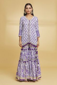 White and purple three fourth sleeves A-line kurta with all over bud bloom garden print and gota lace, sequin highlights. Paired with a matching fleur print and gota lace, thread tassel embellished tiered gharara and dupatta with gota weave border detailing. - Aza Fashions Designer Long Sleeve Purple Palazzo Set, Long Sleeve Purple Palazzo Set For Diwali, Long Sleeve Purple Sharara For Eid, Bohemian Purple Sets With Dupatta, Bohemian Purple Set With Dupatta, Bohemian Purple Wedding Sets, Purple Bohemian Wedding Sets, V Neck Kurti, Jaipur Kurti