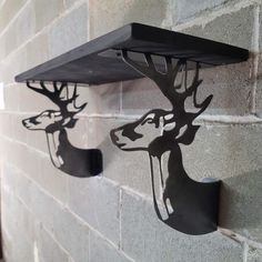 two metal deer heads mounted to the side of a brick wall