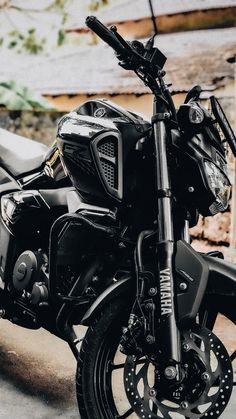 a black motorcycle parked next to a wooden fence