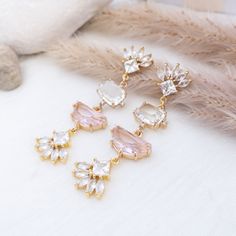 Statement earrings with fan shaped crystal posts and clear and pink crystals Pink Earrings With Sparkling Cubic Zirconia Stones, Glamorous Rose Gold Crystal Earrings With Sparkling Stones, Pink Glamorous Wedding Jewelry, Glamorous Pink Wedding Jewelry, Glamorous Pink Crystal-embellished Jewelry, Pink Crystal Jewelry For Evening, Pink Dangle Chandelier Earrings For Wedding, Pink Crystal Earrings For Wedding, Pink Crystal Wedding Earrings