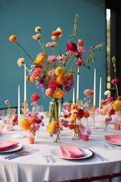 an arrangement of flowers and candles on a table set for a formal dinner or party