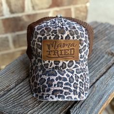 a leopard print hat with the word mama tried written in brown leather on an old wooden bench