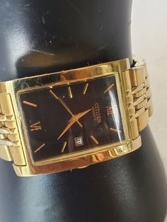 This listing is for a vintage gold tone rectangular shaped Men's Citizen Quartz watch. It has a black face and elegant gold hands and 2 numbers: 12 and 6. There is a date slot that is sent at date 31. This watch came from an estate sale in Thornton, Co. and runs great just needed a new battery. It did not come with the original box but will be send out in a gift box with FREE SHIPPING. I will measure the bezel and band for a good fit. There is some metal wear on the Citizen closure nothing too bad I tried to take close photos so you can see look at photo #7 if this is an issue, please reframe from buying.  Bezel Measure: 1 1/4"L X 1 1/8"W Band measures: 8"L including bezel X 3/4"W Material: gold tone metal, stainless steel fold over band and bezel, rectangular gold tone bezel, black face, Gold Rectangular Watch Accessories For Formal Occasions, Gold Watches With Date Display And Rectangular Dial, Gold Rectangular Watches With Subdials, Classic Gold Square Watch Accessories, Gold Square Watch For Formal Occasions, Retro Gold Rectangular Watches, Retro Gold Watches With Rectangular Dial, Gold Square Analog Watch, Gold Square Analog Watches