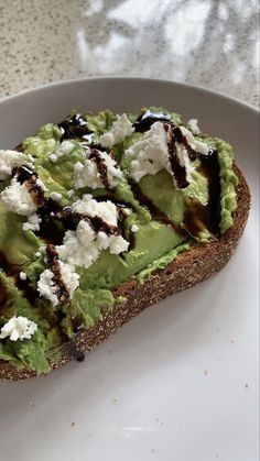 an avocado toast on a white plate with chocolate drizzle