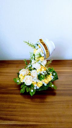 a bouquet of yellow and white flowers sitting on top of a wooden table