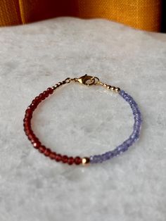 Elegant and dainty, this handmade bracelet features sparkling faceted 3mm Tanzanite and Garnet beads, showcasing a captivating interplay of deep reds and rich blues. Measuring about 7 inches in length, it is finished with a secure gold-filled lobster claw clasp, adding a touch of luxury to this exquisite piece Dainty Faceted Beaded Bracelets For Everyday Wear, Dainty Faceted Beaded Bracelets, Faceted Rondelle Beaded Bracelets As Gift, Faceted Rondelle Crystal Bracelet Gift, Gift Rondelle Faceted Beaded Bracelets, Gift Rondelle Faceted Beads Bracelet, Everyday Faceted Rondelle Bracelets, Dainty Beaded Bracelets For Birthday, Faceted Beaded Bracelets As Gift