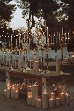 many candles are lit on a table in the middle of an outdoor area with chairs and tables