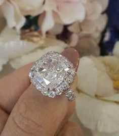 a close up of a person's hand holding a diamond ring