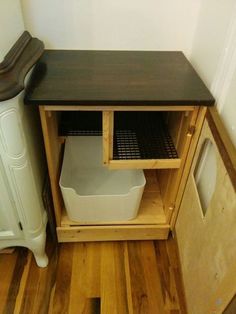 a wooden cabinet sitting next to a trash can on top of a hard wood floor