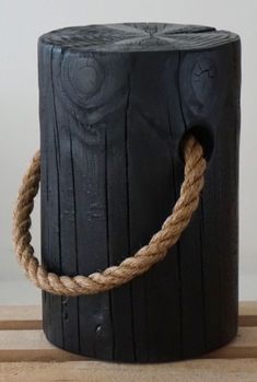 a rope wrapped around the top of a wooden stump on a table next to a white wall